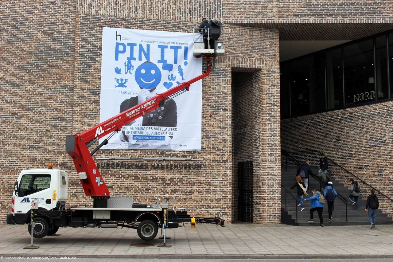 Pin-it! Ophangen van spandoek aan gevel van Europäisches Hansemuseum in Lübeck